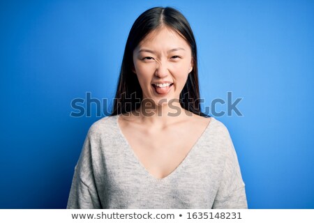 Foto stock: Funny Asian Beautiful Woman Isolated Over Blue Background Showing Tongue