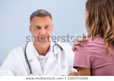 Foto stock: Patient Showing Sore Shoulder To Doctor At Clinic