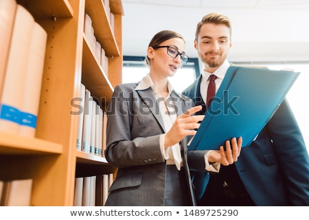 ストックフォト: Lawyers In Library Of Law Firm Discussing Strategy In A Case Holding File