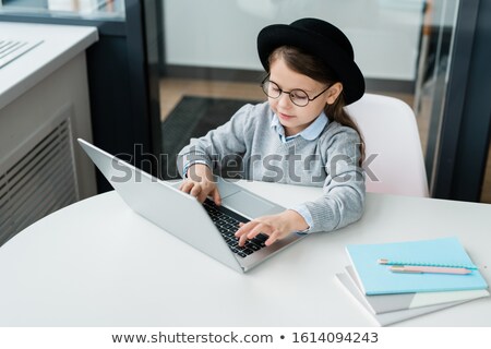 Foto d'archivio: Clever Casual Schoolgirl In Eyeglasses Preparing Homework And Using Laptop