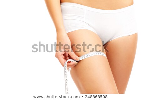 Foto stock: Midsection Of Woman Measuring Thigh