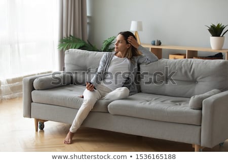 Stok fotoğraf: Attractive Thoughtful Young Woman Sitting And Holding Cellphone