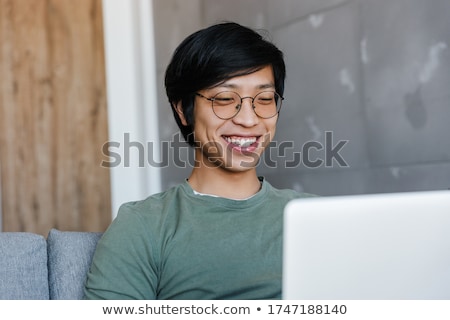 Foto stock: Image Of Positive Asian Guy In Casual Wear And Eyeglasses Worki