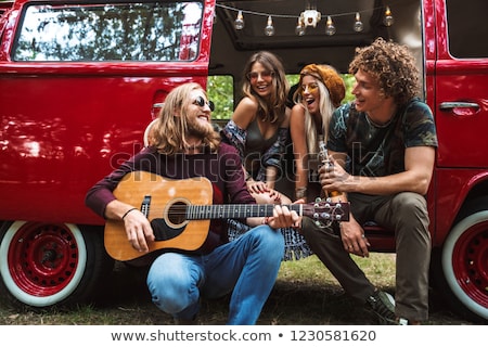 [[stock_photo]]: Group Of Young Hippies Men And Women Laughing And Playing Guita