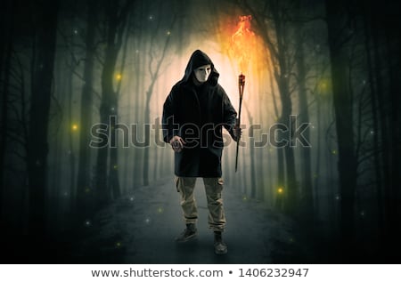 [[stock_photo]]: Man Coming From Dark Forest With Burning Flambeau In His Hand Concept