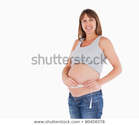 ストックフォト: Pretty Pregnant Woman Measuring Her Belly While Standing Against A White Background