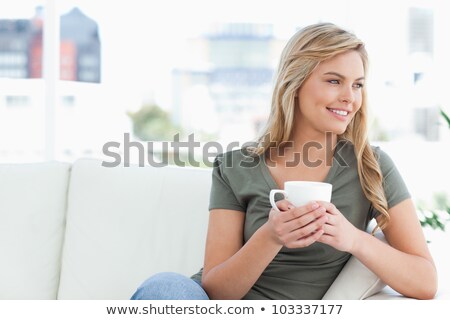 ストックフォト: Woman Smiling While Holding A Coffee Mug In A Living Room