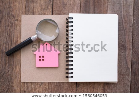Foto d'archivio: Magnifying Glass And Paper House On Table