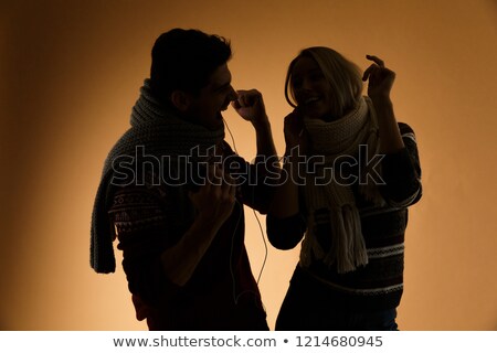 Stock fotó: Silhouettes Of Young Loving Couple In Sweaters Listening Music Isolated Over Beige Background Dancin