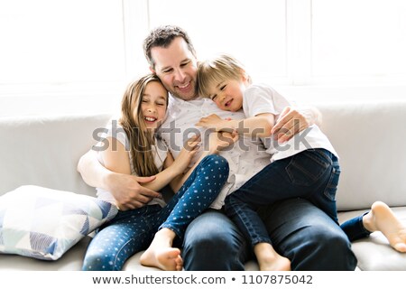 Stock photo: Father And His Nine Years Kid Girl And 5 Years Boy On The Sofa At Home