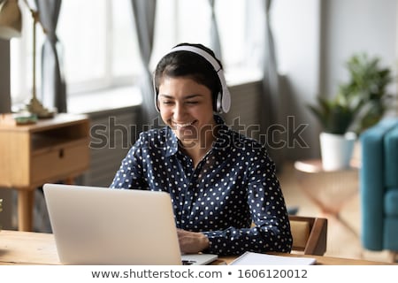 Stockfoto: Young Businesswoman In Headphones Working On A Laptop At Office