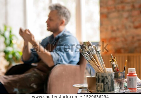 Stock fotó: Two Bunches Of Paintbrushes In Dirty Tin Cans And Jar Of Gouache On Table