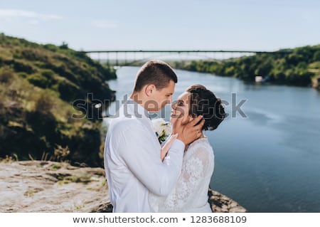 Foto stock: A Stylish Newlyweds Cuddle In Nature On The Background Of Rocks And Cliffs