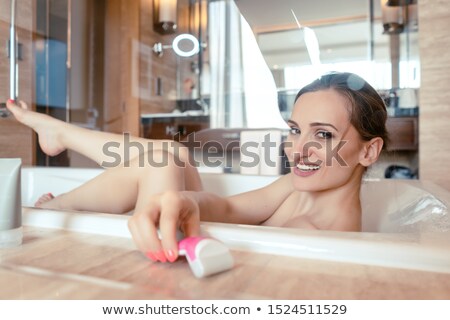 Zdjęcia stock: Woman Having Bath In Hotel Bathtub Grabbing Her Shaver For Hair Removal