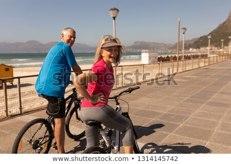 Stock photo: Rear View Of Active Senior Couple Riding A Bicycle On A Promenade At Beach