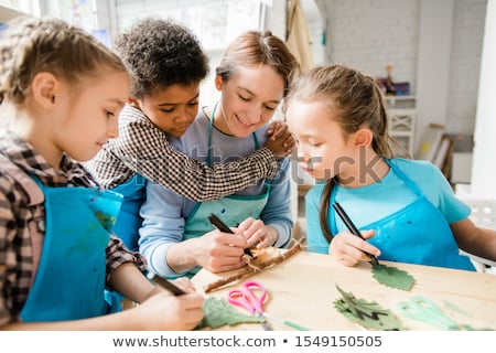 Imagine de stoc: Affectionate Schoolboy Embracing Young Woman Drawing Or Writing With Highlighter