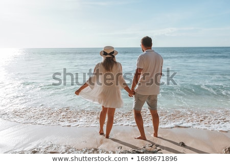 商業照片: Happy Young Romantic Couple Relaxing On The Beach And Watching The Sunset