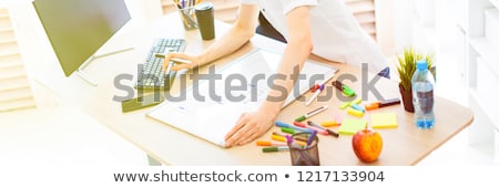 Сток-фото: A Young Man With Glasses And Headphones Stands Near A Computer Desk Holds A Marker In His Hand And