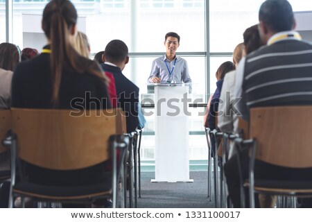 [[stock_photo]]: Front View Of Handsome Young Asian Businessman Speaking In Front Of Business Professionals Sitting A