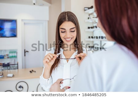 Stockfoto: Woman In Glasses Holding To Head At Optics Store