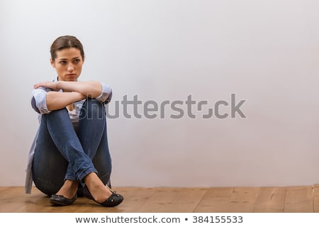 [[stock_photo]]: Girl Sitting On The Floor With Her Legs Crossed And Looking Away