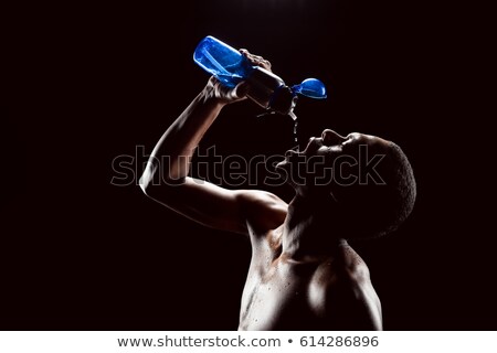 Stock foto: Side View Of Sporty African Man Drinking Water After Training On Black