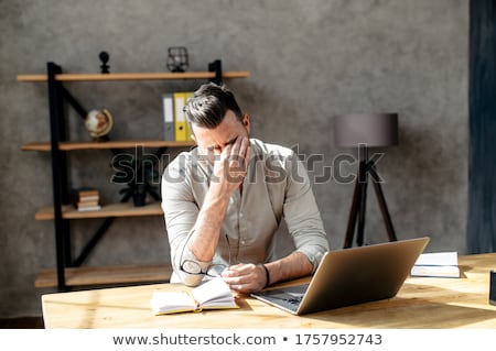 Stockfoto: A Young Man Sits At A Table In The Office Took Off His Glasses And Rubbed His Eyes