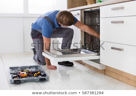 Stock photo: Serviceman Repairing Dishwasher In Kitchen