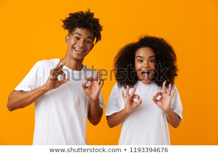 [[stock_photo]]: Young Cute African Couple Posing Isolated Over Yellow Background Showing Okay Gesture