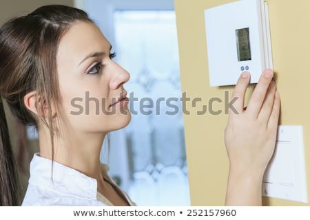 Foto stock: A Woman Set The Thermostat At House