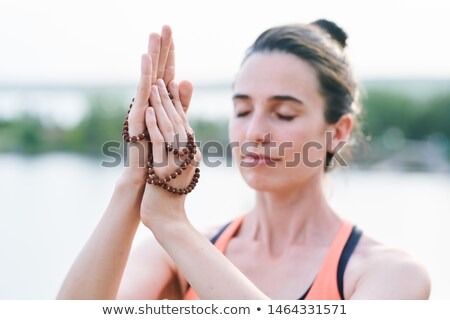 Foto stock: Close Up Of Serene Woman With Closed Eyes Touching Beads While Meditating