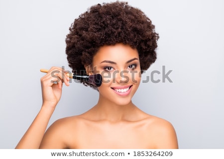 Stockfoto: Beautiful Young Woman Applying Foundation On Her Face With A Make Up Brush Isolated On Gray Backgrou