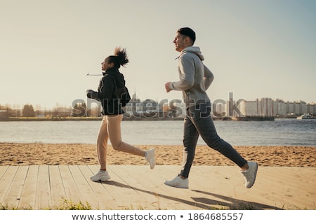 Сток-фото: Couple In Sports Clothes Running Along On Beach