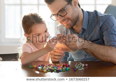 Foto stock: Happy Girl Sitting At The Table With Thread