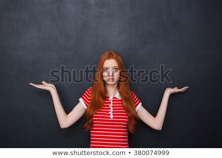 Zdjęcia stock: Confused Woman Holding Copyspace On Both Palms Over Chalkboard Background