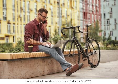 Stock photo: Happy Guy Sitting On Bicycle And Talking At Phone