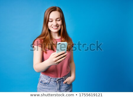 [[stock_photo]]: Smiling Ginger Woman In Shirt And Jeans Using Smartphone