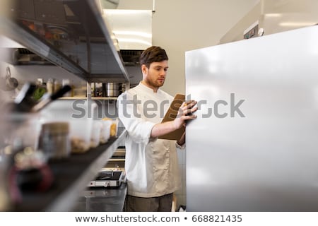 Foto stock: Chef With Clipboard Doing Inventory At Kitchen