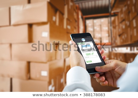 Stockfoto: Delivery Man With Smartphone And Box At Warehouse