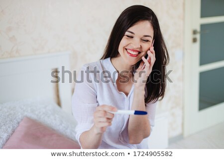 Foto stock: Happy Woman With Pregnancy Test In Her Home