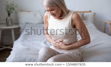Foto stock: Woman With Stomach Pains In Bed