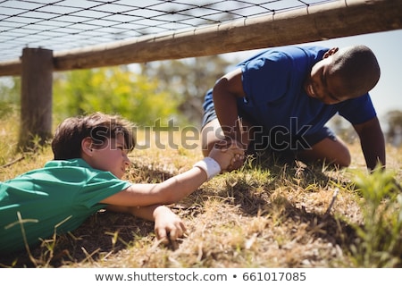 Stok fotoğraf: Kids Crawling Under The Net During Obstacle Course Training