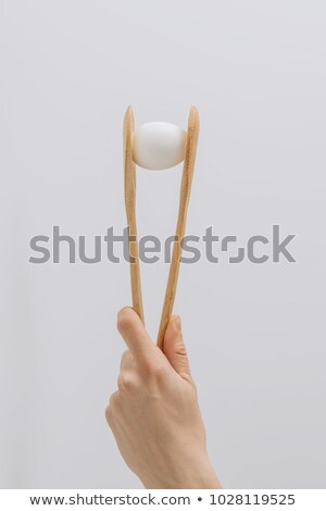 Stock fotó: Cropped Image Of Hand Holding Wooden Tongs With White Egg