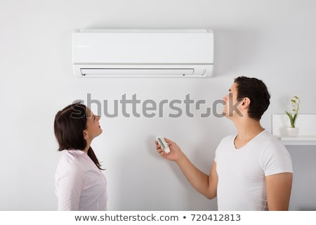 Foto d'archivio: Couple Adjusting Temperature Of Air Conditioner