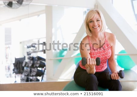 Stock photo: Woman Using Hand Weights On Swiss Ball At Gym