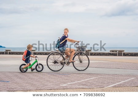 ストックフォト: Happy Family Is Riding Bikes Outdoors And Smiling Mom On A Bike And Son On A Balancebike