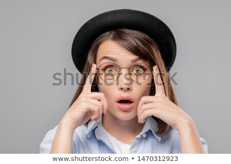 Young Astonished Female In Hat And Eyeglasses Looking At You Stockfoto © Pressmaster
