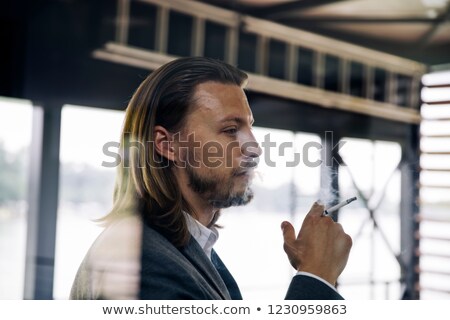 [[stock_photo]]: Side View At Young Businessman Enjoying His Cigar