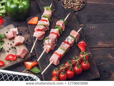 Stock foto: Raw Pork Kebab With Paprika On Chopping Board With Fresh Vegetables And Disposable Charcoal Grill On