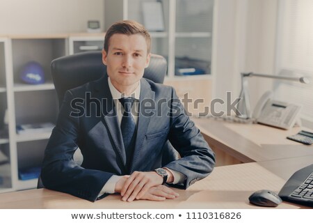 Foto d'archivio: Half Length Portrait Of Handsome Prosperous Male Manager Sits At Cabinet Looks Directly Into Camera